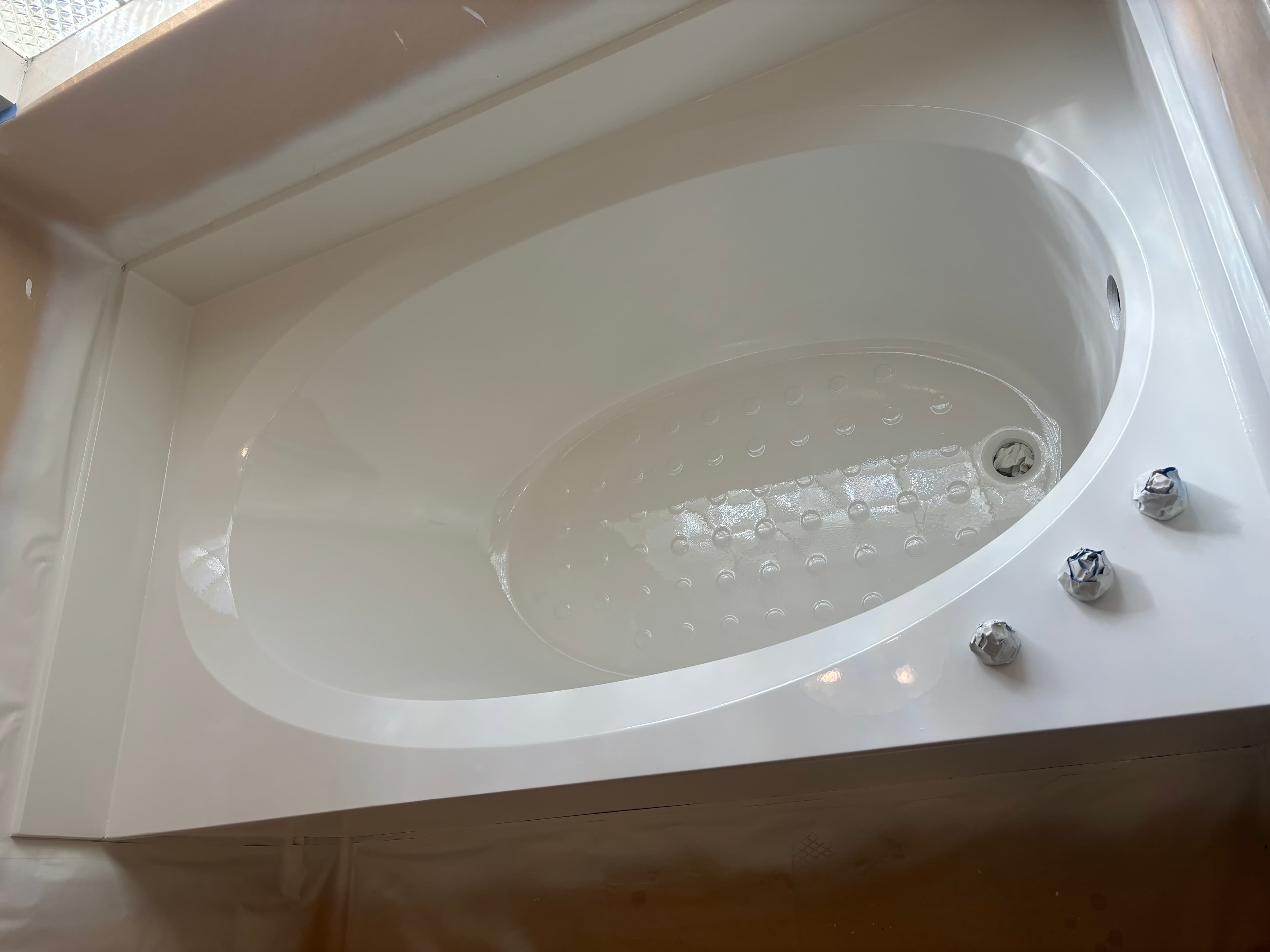White oval bathtub with a textured non-slip bottom, prepared for a bathroom refinishing project.
